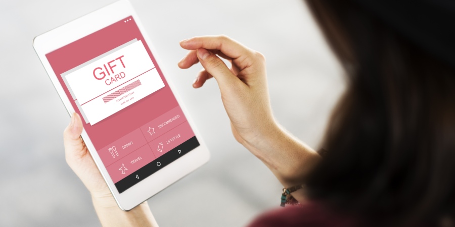 Person holding a tablet displaying an online gift card.